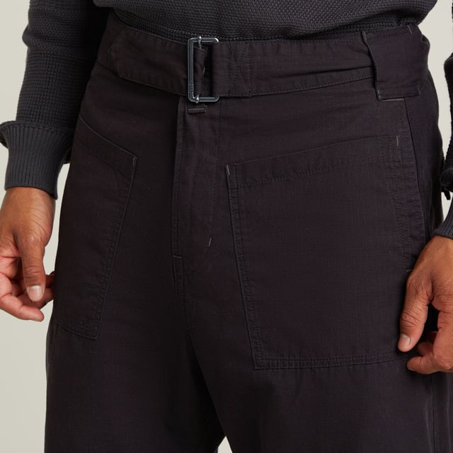 Zip fly. Side seam pockets, patched-on waist pockets. Flap pockets at the back, snap buttons. Belt. Adjustable leg width, tab. Button & zip closure. Mid waist. This Fatigue pant is designed in a relaxed tapered fit. The pleats at the side and the tabs at the ankle add to it. These pants combine side seam pockets with pockets at the front. The backside shows flap pockets with a snap button closure. Use the belt to finetune the fit. 100% Cotton. Rigid. Tapered