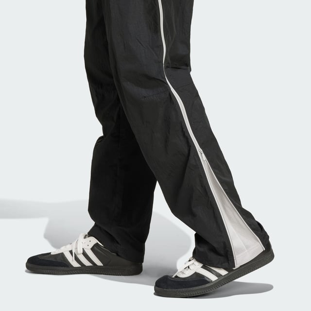 Inspired by the 2000s-era archive, these track pants from adidas give you a minimalist look with maximum impact. Long zippers along the sides with airy mesh underneath keep you comfortable with fashion in focus from the moment you pull them on. They have a loose fit with woven fabric that's lightweight yet durable. A floating Trefoil and 3-Stripes down the right leg show your allegiance to the brand with sport heritage.  - Loose fit - Drawcord on elastic waist - 100% polyamide (recycled) - Side-panel zips with mesh underneath  Shipped by adidas