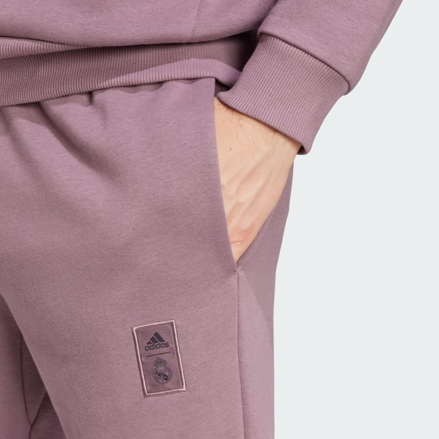 Wherever you go, show your football allegiance in style. Crafted for comfort, these adidas Real Madrid pants are built from soft fleece. Zips keep the fit tucked in at the ankles and a drawcord waist ensures you find the ideal fit. Sewn onto one leg, a club badge shares your team pride.  - Regular fit - Drawcord on elastic waist - 70% cotton, 30% polyester (recycled) - Side pockets - Back patch pocket - Ankle zips - Real Madrid sewn-on crest  Shipped by adidas