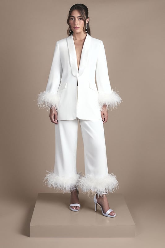 Feather Trim Single Breasted Tux Style Wedding Blazer Luxurious tuxedo-style blazer with dramatic feather trim detailing at the cuffs
Elegant shawl collar design creates a sophisticated neckline
Single-breasted fastening with subtle button closure for a clean silhouette
Tailored fit with gentle waist definition for a flattering shape
Versatile styling piece that works beautifully as bridal outerwear or statement evening attire
Make a striking entrance on your special day with this show-stopping Coast tuxedo blazer. The sumptuous satin fabric creates a lustrous finish while the statement feather trim adds theatrical flair to this contemporary bridal piece. The clean lines of the shawl collar and single-breasted design offer a modern take on classic tailoring, perfect for the fashion-forward bride. Style with the matching feather-trimmed trousers as seen for a complete bridal power suit, or layer over a sleek column dress for your evening reception. Complete the look with statement drop earrings and elegant heeled sandals for a bridal ensemble that beautifully balances tradition with high-fashion sensibility. This versatile piece transitions effortlessly to other special occasions beyond your wedding day.