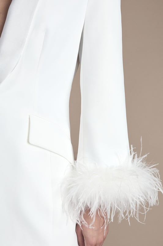 Feather Trim Single Breasted Tux Style Wedding Blazer Luxurious tuxedo-style blazer with dramatic feather trim detailing at the cuffs
Elegant shawl collar design creates a sophisticated neckline
Single-breasted fastening with subtle button closure for a clean silhouette
Tailored fit with gentle waist definition for a flattering shape
Versatile styling piece that works beautifully as bridal outerwear or statement evening attire
Make a striking entrance on your special day with this show-stopping Coast tuxedo blazer. The sumptuous satin fabric creates a lustrous finish while the statement feather trim adds theatrical flair to this contemporary bridal piece. The clean lines of the shawl collar and single-breasted design offer a modern take on classic tailoring, perfect for the fashion-forward bride. Style with the matching feather-trimmed trousers as seen for a complete bridal power suit, or layer over a sleek column dress for your evening reception. Complete the look with statement drop earrings and elegant heeled sandals for a bridal ensemble that beautifully balances tradition with high-fashion sensibility. This versatile piece transitions effortlessly to other special occasions beyond your wedding day.