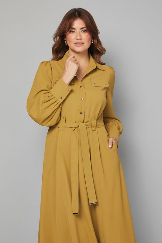 Elegant midi dress crafted from lightweight crepe fabric for comfortable all-day wear
        Sophisticated collared neckline with button-through front design for classic appeal
        Statement balloon sleeves with neat cuffs adding a contemporary touch to a timeless silhouette
        Practical chest pockets providing both style and functionality
        Flattering belted waist that cinches and defines your figure beautifully
    
    This versatile Wallis midi dress combines sophistication with everyday wearability. The flowing crepe fabric drapes elegantly while the belted waist creates a flattering silhouette that works for various body types. Style with knee-high boots as shown for an effortlessly chic daytime look perfect for lunch dates or family gatherings. For a more casual approach, pair with white trainers and a denim jacket. The practical pocket details and comfortable fit make this an ideal choice for busy days when you need to look polished without sacrificing comfort. Transition from day to evening by swapping boots for ballet flats and adding statement earrings. This dress will quickly become a cornerstone of your wardrobe, offering endless styling possibilities throughout the seasons.