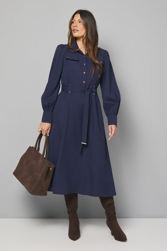 Elegant midi dress crafted from lightweight crepe fabric for comfortable all-day wear
        Sophisticated collared neckline with button-through front design for classic appeal
        Statement balloon sleeves with neat cuffs adding a contemporary touch to a timeless silhouette
        Practical chest pockets providing both style and functionality
        Flattering belted waist that cinches and defines your figure beautifully
    
    This versatile Wallis midi dress combines sophistication with everyday wearability. The flowing crepe fabric drapes elegantly while the belted waist creates a flattering silhouette that works for various body types. Style with knee-high boots as shown for an effortlessly chic daytime look perfect for lunch dates or family gatherings. For a more casual approach, pair with white trainers and a denim jacket. The practical pocket details and comfortable fit make this an ideal choice for busy days when you need to look polished without sacrificing comfort. Transition from day to evening by swapping boots for ballet flats and adding statement earrings. This dress will quickly become a cornerstone of your wardrobe, offering endless styling possibilities throughout the seasons.