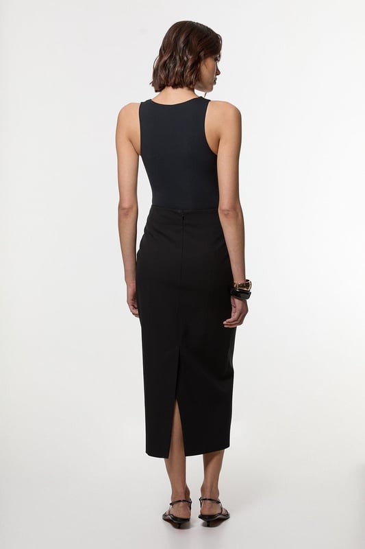 This Karen Millen tailored midi pencil skirt offers the perfect balance of sophistication and practicality for your everyday wardrobe. The compact stretch fabric moulds to your silhouette whilst ensuring all-day comfort and ease of movement. Style with a crisp sleeveless top and strappy sandals for a refined daytime look, or pair with a structured blazer for an effortlessly stylish ensemble perfect for family gatherings or lunch with friends. The functional pocket detail adds a contemporary touch to this timeless piece, whilst the below-knee length creates a flattering line that works brilliantly with both flats and low heels. This versatile skirt can be dressed down with a casual knit and trainers for weekend brunches or styled with a silk blouse for more polished daywear occasions.  Sleek midi pencil skirt Practical side pocket detail Elegant midi length Versatile design