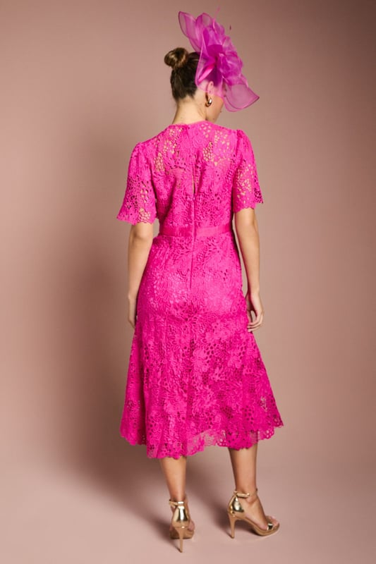 Exquisite lace midi dress with intricate floral pattern
        Elegant bow belt accentuates the waistline
        Flattering round neckline and short sleeves
        Scalloped hem adds a delicate touch
        Midi length perfect for formal occasions
    
    This stunning lace midi dress radiates sophistication and grace, making it an ideal choice for weddings, races, or any formal event where you want to make a lasting impression. The intricate floral lace pattern adorns the entire dress, creating a romantic and feminine silhouette. The bow belt cinches the waist beautifully, enhancing your figure and adding a charming detail. Style this dress with a matching fascinator, as shown, for a coordinated look that's sure to turn heads. Pair with strappy metallic heels and a clutch bag to complete your ensemble. For cooler evenings, drape a lightweight pashmina over your shoulders. This versatile piece can be dressed up or down, making it a valuable addition to your occasion wear wardrobe.