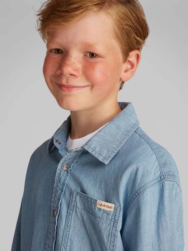 Introducing the Boys Relaxed Chambray Shirt in Blue by Calvin Klein, the quintessential blend of sophistication and comfort for SS2025. Ideal for every young gentleman's wardrobe, this shirt promises both style and ease. Key features include Classic Chambray Crafted with premium cotton chambray, ensuring a soft and breezy feel perfect for sunny days. Versatile Blue Hue A deep, versatile blue that complements any outfit, ideal for both casual and formal occasions. Signature Detailing Enhanced with Calvin Klein's discreet branding, adding a touch of exclusive luxury. Easy Care Machine washable and resilient, designed for the effortless upkeep required by every young adventurer.Elevate your boy's style with this timeless piece from Calvin Klein. Order now to capture the essence of SS2025!