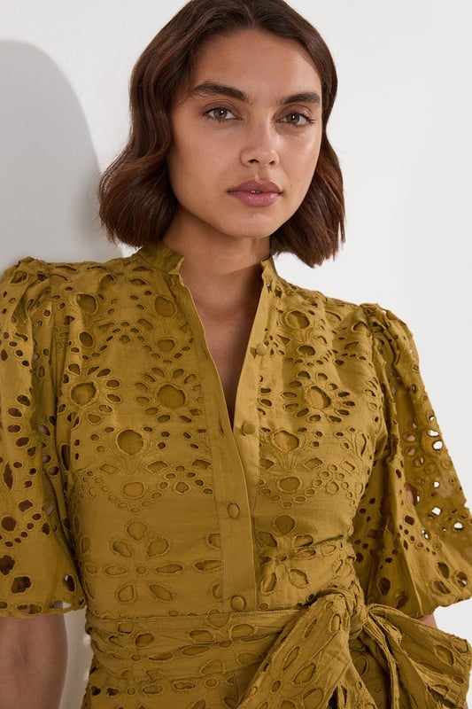 This Karen Millen cotton broderie mini dress combines timeless charm with contemporary styling. The breathable fabric ensures comfort for all-day wear, whilst the intricate eyelet detailing adds texture and visual interest. Style with leather sandals and a woven basket bag for a casual summer look or with espadrille wedges and delicate gold jewellery for elevated occasions. The adjustable tie waist allows for a customised fit, making this piece a flattering addition to your warm-weather wardrobe.  Intricate broderie anglaise pattern Collared neckline with button-down front detail Flutter sleeves Adjustable tie waist Playful ruffle hem detail