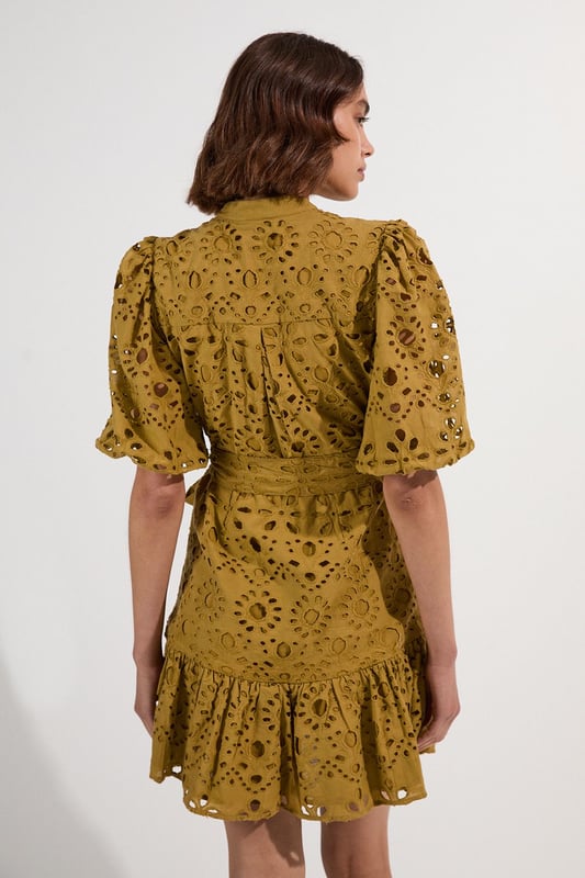 This Karen Millen cotton broderie mini dress combines timeless charm with contemporary styling. The breathable fabric ensures comfort for all-day wear, whilst the intricate eyelet detailing adds texture and visual interest. Style with leather sandals and a woven basket bag for a casual summer look or with espadrille wedges and delicate gold jewellery for elevated occasions. The adjustable tie waist allows for a customised fit, making this piece a flattering addition to your warm-weather wardrobe.  Intricate broderie anglaise pattern Collared neckline with button-down front detail Flutter sleeves Adjustable tie waist Playful ruffle hem detail