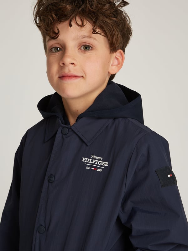Unveil the essence of style with the Tommy Hilfiger Boys Coach 3 in 1 Jacket in sleek black, an essential for SS2025. Each detail is finely crafted for the fashionable boy Versatile Design Transforms for varying weather, ensuring stylish practicality. Superior Fabric Crafted with premium materials for unmatched comfort durability. Iconic Branding Subtle yet striking logos for that quintessential Tommy Hilfiger charm.Refine his look with this exquisite piece. Secure this timeless jacket today and let your young gentleman step out in unparalleled sophistication!