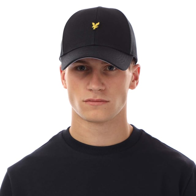 Außenmaterial (%): 100% Baumwolle. Marke: Lyle & Scott. Gewebe: Schwerer Köperstoff. Design: Gesticktes Logo. Design mit 6 Segmenten, Oben mit Knopf, Abgerundeter Kopf, Mit umstickten Ösenlöchern, Genähte Krempe. Verstellbarer Gurt.