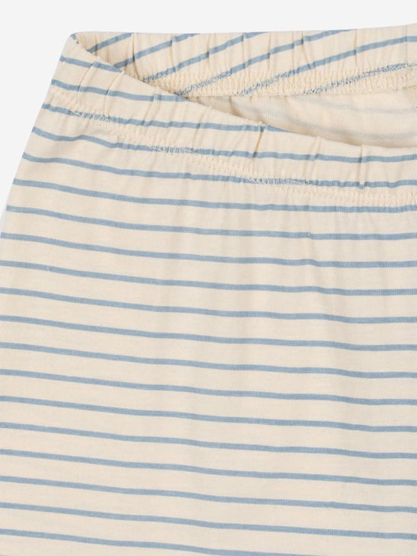 Konges Sløjd incorporate beautiful, eco-friendly technology into their charming aesthetics. This boys stripe blue pyjama set consists of a nightgown and a pair of night trousers in white with narrow, blue stripes. The nightgown has a golden print of a moon and a cute brown bear holding a cushion. The matching trousers come with an elastic edge at the waist to provide the utmost comfort. Nightgown Round Neckline, Long Sleeves, Wide Edges Trousers Wide Edges 100 Organic Cotton