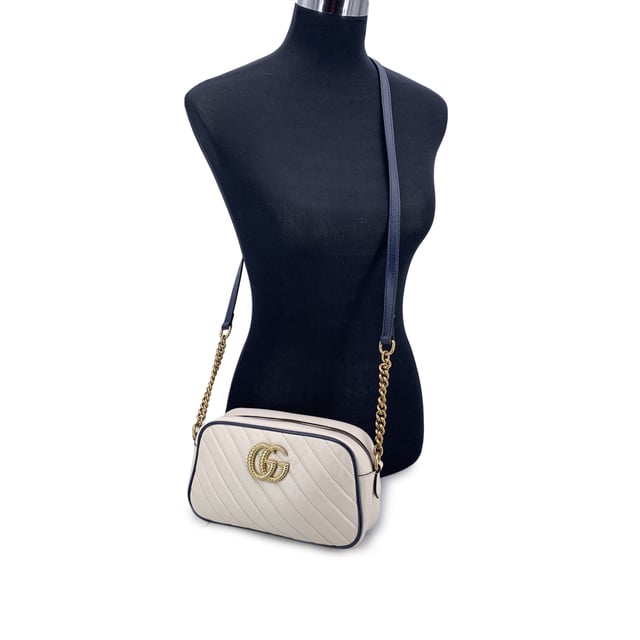 VINTAGE, RRP AS NEW
This beautiful Bag will come with a Certificate of ity provided by Entrupy. The certificate will be provided at no further cost.  Step into timeless elegance with this beautiful Gucci GG Marmont Small Zip Around Shoulder Bag, a true gem for lovers of vintage luxury. Crafted in soft white matelassé quilted leather, the bag is gracefully framed with navy blue leather trim-a nod to nautical chic that never goes out of style.  At the heart of its design, the iconic gold metal Torchon GG logo gleams proudly on the front, echoing Gucci's rich heritage. The bag zips open at the top to reveal a refined microfibre interior, complete with a convenient side pocket for your essentials.  The shoulder strap-an artful blend of adjustable navy leather and antique gold chain-lets you wear it crossbody or snug on the shoulder, adding versatility to its elegance. Inside, a discreet 'Gucci - Made in Italy' tag whispers top crftmanship, backed by a serial number hidden on its reverse.  A striking yet subtle piece, this GG Marmont model captures the spirit of classic Italian craftsmanship with a modern, collector-worthy twist.  Condition Rating: A - EXCELLENTCondition Details: Gently used. Minimal wear of use on leather trim. Minimal wear of use on the internal lining. Please check the photos carefully and ask if you need to know more details or if you have any doubts.Measurements (cm):Depth: 6.4Height: 12.7Length: 24.1Other Details: Dustbag? NoKeys? NoBox? No Measurments:  width: 64 mm length: 241 mm height: 127 mm strap length: 0 mm handle drop: 0 mm
