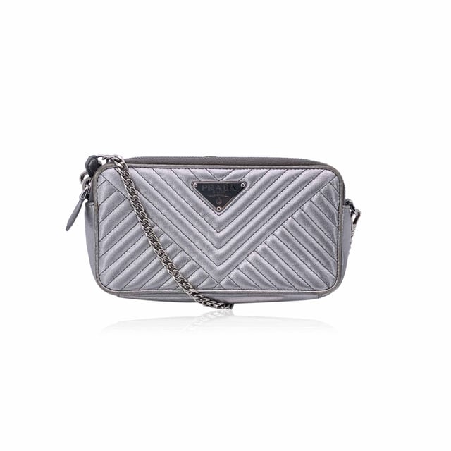 Empfohlener Verkaufspreis
Diese wunderschöne Tasche wird mit einem Qualitätszertifikat von Entrupy geliefert. Das Zertifikat wird kostenlos zur Verfügung gestellt. Die Prada Black Diagramme Leather Double Zip Shoulder Bag ist der Inbegriff raffinierter Eleganz und moderner Raffinesse. Diese Tasche aus glattem, silbernem Metallleder mit Steppung erstrahlt in zeitlosem Luxus. Das ikonische emaillierte Prada-Dreieckslogo auf der Vorderseite verleiht einen kräftigen, charakteristischen Touch, während die silberfarbenen Beschläge das elegante, futuristische Design der Tasche ergänzen. Die Tasche verfügt über zwei Reißverschlussfächer, die jeweils mit einer Kombination aus Textil und Leder gefüttert sind und reichlich Platz für Ihre wichtigsten Dinge bieten. Im Inneren befinden sich in jedem Fach drei Kartenfächer, sodass Sie stilvoll Ordnung halten können. Das zentrale Einsteckfach bietet zusätzlichen Stauraum für Dinge, die Sie getrennt aufbewahren möchten. Mit einem abnehmbaren Kettenschulterriemen kann dieses vielseitige Stück über der Schulter oder als schicke Clutch getragen werden. Mit der Innengravur „Prada – Made in Italy“ ist diese Tasche ein Beweis für die Handwerkskunst und zeitlose Anziehungskraft der Marke. Perfekt für jeden Anlass, ist die Prada Diagramme Woc Geldbörse an der Kette ebenso praktisch wie schön – ein sofortiger Klassiker. Zustandsbewertung: B – SEHR GUTER ZUSTAND Zustandsdetails: Einige Gebrauchsspuren am Leder (insbesondere an den Rändern der Tasche). Ein rosa Fleck auf dem Leder innen. Bitte sehen Sie sich die Fotos sorgfältig an und fragen Sie nach, wenn Sie weitere Details benötigen oder Fragen haben. Maße (cm): Tiefe: 2,5 Höhe: 10,2 Länge: 19,1 Weitere Details: Staubbeutel? Nein Schlüssel? Nein Box? Nein Maße: Breite: 25 mm Länge: 191 mm Höhe: 102 mm Riemenlänge: 0 mm Griffabfall: 0 mm