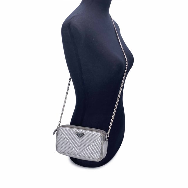 Empfohlener Verkaufspreis
Diese wunderschöne Tasche wird mit einem Qualitätszertifikat von Entrupy geliefert. Das Zertifikat wird kostenlos zur Verfügung gestellt. Die Prada Black Diagramme Leather Double Zip Shoulder Bag ist der Inbegriff raffinierter Eleganz und moderner Raffinesse. Diese Tasche aus glattem, silbernem Metallleder mit Steppung erstrahlt in zeitlosem Luxus. Das ikonische emaillierte Prada-Dreieckslogo auf der Vorderseite verleiht einen kräftigen, charakteristischen Touch, während die silberfarbenen Beschläge das elegante, futuristische Design der Tasche ergänzen. Die Tasche verfügt über zwei Reißverschlussfächer, die jeweils mit einer Kombination aus Textil und Leder gefüttert sind und reichlich Platz für Ihre wichtigsten Dinge bieten. Im Inneren befinden sich in jedem Fach drei Kartenfächer, sodass Sie stilvoll Ordnung halten können. Das zentrale Einsteckfach bietet zusätzlichen Stauraum für Dinge, die Sie getrennt aufbewahren möchten. Mit einem abnehmbaren Kettenschulterriemen kann dieses vielseitige Stück über der Schulter oder als schicke Clutch getragen werden. Mit der Innengravur „Prada – Made in Italy“ ist diese Tasche ein Beweis für die Handwerkskunst und zeitlose Anziehungskraft der Marke. Perfekt für jeden Anlass, ist die Prada Diagramme Woc Geldbörse an der Kette ebenso praktisch wie schön – ein sofortiger Klassiker. Zustandsbewertung: B – SEHR GUTER ZUSTAND Zustandsdetails: Einige Gebrauchsspuren am Leder (insbesondere an den Rändern der Tasche). Ein rosa Fleck auf dem Leder innen. Bitte sehen Sie sich die Fotos sorgfältig an und fragen Sie nach, wenn Sie weitere Details benötigen oder Fragen haben. Maße (cm): Tiefe: 2,5 Höhe: 10,2 Länge: 19,1 Weitere Details: Staubbeutel? Nein Schlüssel? Nein Box? Nein Maße: Breite: 25 mm Länge: 191 mm Höhe: 102 mm Riemenlänge: 0 mm Griffabfall: 0 mm