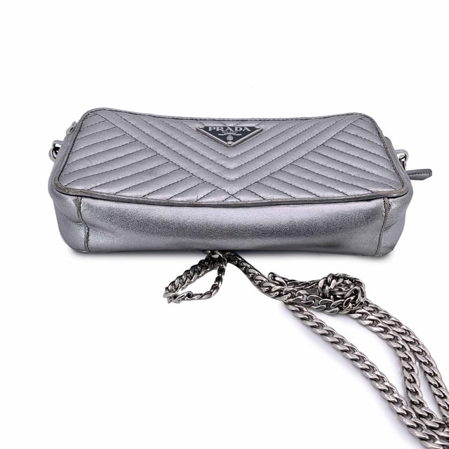Empfohlener Verkaufspreis
Diese wunderschöne Tasche wird mit einem Qualitätszertifikat von Entrupy geliefert. Das Zertifikat wird kostenlos zur Verfügung gestellt. Die Prada Black Diagramme Leather Double Zip Shoulder Bag ist der Inbegriff raffinierter Eleganz und moderner Raffinesse. Diese Tasche aus glattem, silbernem Metallleder mit Steppung erstrahlt in zeitlosem Luxus. Das ikonische emaillierte Prada-Dreieckslogo auf der Vorderseite verleiht einen kräftigen, charakteristischen Touch, während die silberfarbenen Beschläge das elegante, futuristische Design der Tasche ergänzen. Die Tasche verfügt über zwei Reißverschlussfächer, die jeweils mit einer Kombination aus Textil und Leder gefüttert sind und reichlich Platz für Ihre wichtigsten Dinge bieten. Im Inneren befinden sich in jedem Fach drei Kartenfächer, sodass Sie stilvoll Ordnung halten können. Das zentrale Einsteckfach bietet zusätzlichen Stauraum für Dinge, die Sie getrennt aufbewahren möchten. Mit einem abnehmbaren Kettenschulterriemen kann dieses vielseitige Stück über der Schulter oder als schicke Clutch getragen werden. Mit der Innengravur „Prada – Made in Italy“ ist diese Tasche ein Beweis für die Handwerkskunst und zeitlose Anziehungskraft der Marke. Perfekt für jeden Anlass, ist die Prada Diagramme Woc Geldbörse an der Kette ebenso praktisch wie schön – ein sofortiger Klassiker. Zustandsbewertung: B – SEHR GUTER ZUSTAND Zustandsdetails: Einige Gebrauchsspuren am Leder (insbesondere an den Rändern der Tasche). Ein rosa Fleck auf dem Leder innen. Bitte sehen Sie sich die Fotos sorgfältig an und fragen Sie nach, wenn Sie weitere Details benötigen oder Fragen haben. Maße (cm): Tiefe: 2,5 Höhe: 10,2 Länge: 19,1 Weitere Details: Staubbeutel? Nein Schlüssel? Nein Box? Nein Maße: Breite: 25 mm Länge: 191 mm Höhe: 102 mm Riemenlänge: 0 mm Griffabfall: 0 mm