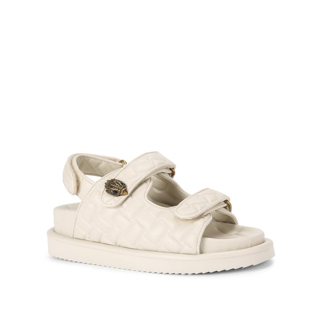 The Kurt Geiger Orson sandal features a bone soft upper with weave quilting pattern. The straps are velcro with an antiqued brass eagle head emblem sat on top. Over stitched quilted insole with padding, seen across the collections.