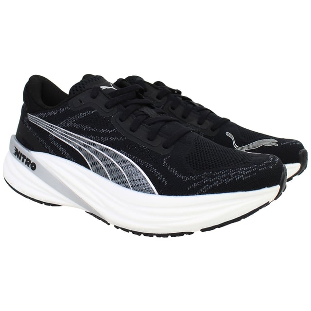 Puma Magnify Nitro 2 Womens Black Running Shoes The PUMA Magnify NITRO 2 Women’s Black is a high-stack, max‑cushioned trainer crafted for daily miles and long-distance comfort. Featuring full-length NITRO foam and a grippy outsole, these shoes deliver soft, responsive cushioning with standout traction and durability. With its sleek black colorway, engineered knit upper, and supportive feel, this edition offers both performance and everyday style.
Key Features
Full-Length NITROFOAM™ Midsole
Puma’s nitrogen-infused foam delivers plush yet responsive cushioning across the entire footbed—perfect for base miles and recovery runs.
Engineered Knit Upper with PWRTAPE Reinforcements
Premium knit fabric molds to the foot for comfort and breathability, while strategic overlay tape adds structural support and a secure fit.
PUMAGRIP Rubber Outsole with Targeted Coverage
Durable traction zones at key contact areas ensure reliable grip and stability on roads—even in damp conditions.
Generous Stack Height with Smooth Transition
Approximately 40 mm heel, 30 mm forefoot, and a 10 mm drop deliver an elevated, rocker-like gait without stiffness.
Moulded Heel Collar and Padded Tongue
Enhances rear-foot comfort and lockdown, reducing heel slippage and irritation on longer runs.