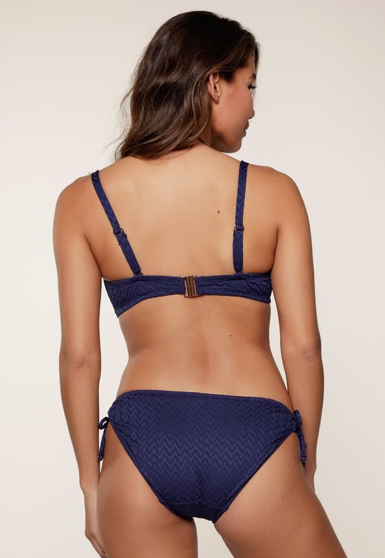 Rise & shine in dieser fantastischen Serie! Diese Modelle ziehen mit ihrem luxuriösen, strukturierten Stoff und dem goldenen Accessoire die Blicke auf sich. Der Bikini ist vorgeformt, hat verstellbare Schulterträger und Bügel. Dadurch ist dieser Bikini auch für große Größen sehr gut geeignet.