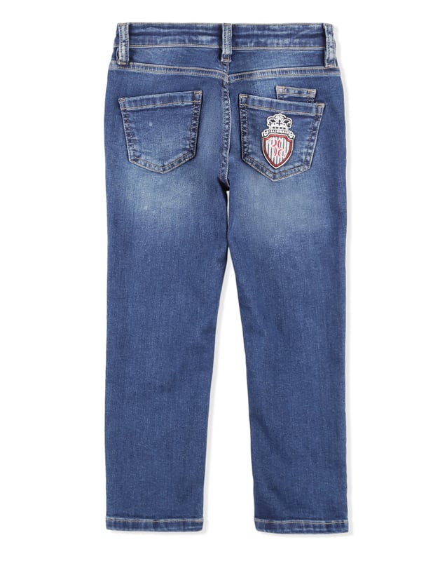 Los clásicos pantalones de denim desgastado de cinco bolsillos son indispensables, incluso en el armario de un niño. Este modelo incluye un botón de metal en la cintura. El bolsillo trasero derecho está adornado con un parche con el icónico emblema de la firma bordado. Corte: Regular.