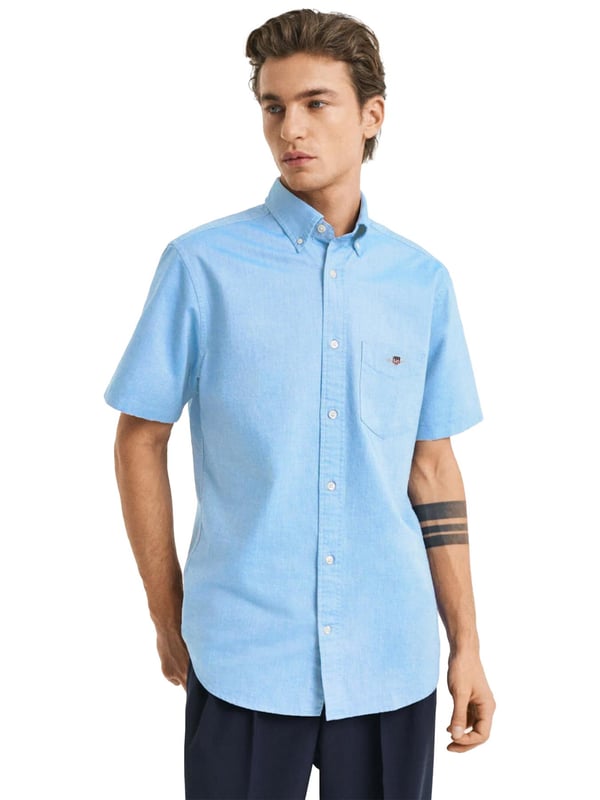 Clásica y versátil, la camisa Oxford es una prenda esencial de estilo smart-casual confeccionada en algodón resistente. Diseñada con corte regular y mangas cortas, es perfecta para los meses más cálidos. Sus detalles incluyen un cuello abotonado, bajo curvado, bolsillo en el pecho con bordado de escudo y una tabla en la espalda con presilla para mayor comodidad y estilo.