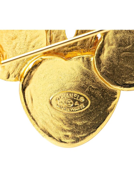 This brooch features a gold-tone metal body and a back pin closure.Brand: Chanel VintageCondition: PrelovedType: Costume BroochRating: B+Main Material: MetalDimensions (LxWxD): 4x4x0Comments: Exterior Back Scratched. Lock Scratched. Exterior Front Scratched.