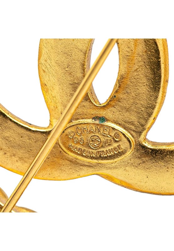 This brooch features a gold-tone metal body and a back pin closure.Brand: Chanel VintageCondition: PrelovedType: Costume BroochRating: ABMain Material: MetalDimensions (LxWxD): 5.5x5.5x0Comments: Exterior Back Discolored Scratched. Lock Scratched. Exterior Front Discolored Scratched.