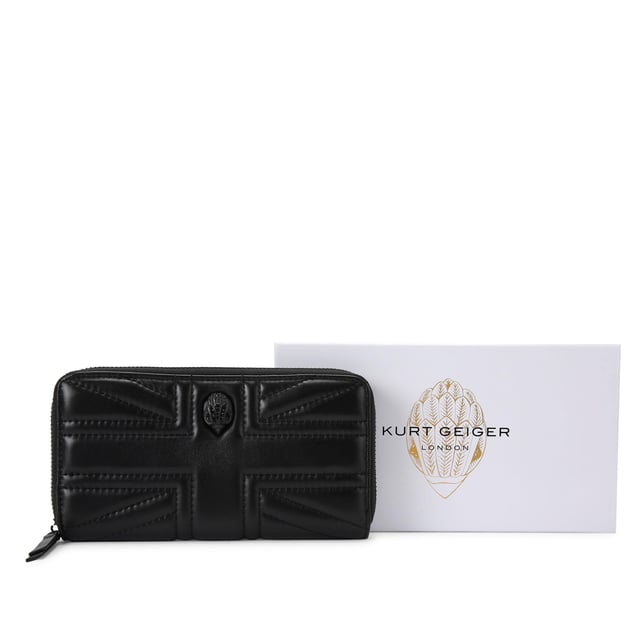 This Kurt Geiger Union Jack Drench Zip Around Purse features a black leather exterior with overstitch quilting creating a Union Jack design. There is a black eagle head with crystals on the front. Dimensions: 10cm (H), 19cm (L), 2cm (D).