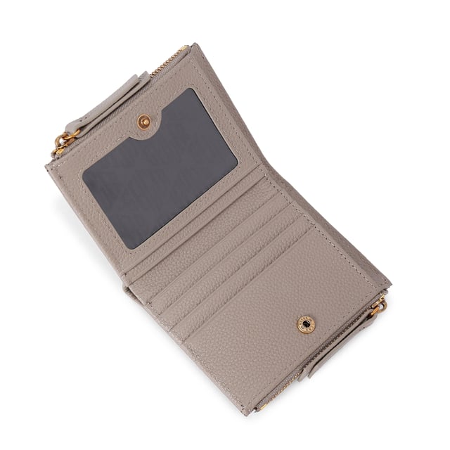 The Greenwich Mini Purse features a taupe grained leather exterior. There is an antiqued brass eagle head and branding on the front. 9cm (H), 11cm (L), 2cm (D).