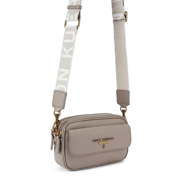 This Kurt Geiger 2Zip Greenwich Cross Body bag is crafted in a taupe grained leather. There is a flat pocket on the back and a magnetic snap closure pocket on the front. There is antiqued brass branding on the front flap. Dimensions: 14cm (H), 23cm (L), 7cm(D). Strap length: 132cm.