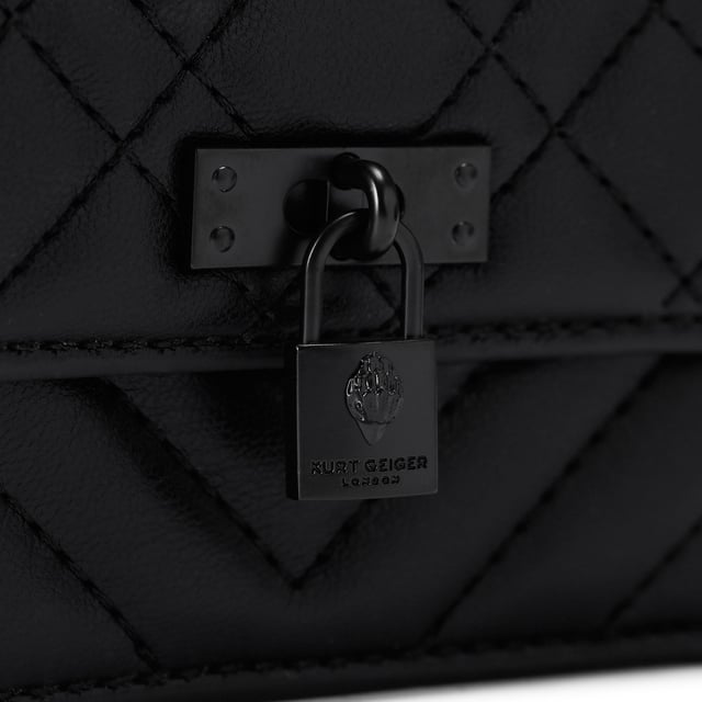 This Kurt Geiger Micro Drench Brixton bag features a black leather alternative exterior with overstitch quilting on the exterior. There is an antiqued brass branded lock on the front flap. Dimensions: 7.5cm (H), 11cm (L), 3cm (D). Strap length: 121cm.