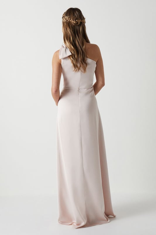 Elegant one shoulder design with a sophisticated bow detail
        Flowing satin fabric that drapes beautifully for a graceful silhouette
        Flattering fitted bodice transitioning into a floor-length skirt
        Subtle wrap-effect hemline creating movement and dimension
        Designed specifically for bridesmaids to complement the bridal party
    
    This enchanting Coast bridesmaids dress combines timeless elegance with contemporary design. The one shoulder neckline with its delicate bow detail creates a refined asymmetric look that photographs beautifully from every angle. The fitted bodice gently hugs your figure before flowing into a graceful floor-length skirt with a subtle wrap effect that adds movement as you walk down the aisle. Perfect for the bridal party, this dress can be styled with delicate jewellery and an elegant updo to mirror the model's sophisticated half-up hairstyle. Complete your bridesmaids look with strappy heels and a small clutch that coordinates with the wedding colour scheme. The satin fabric catches the light beautifully, ensuring you'll shine in your supporting role on the special day whilst maintaining the perfect balance of sophistication and grace.