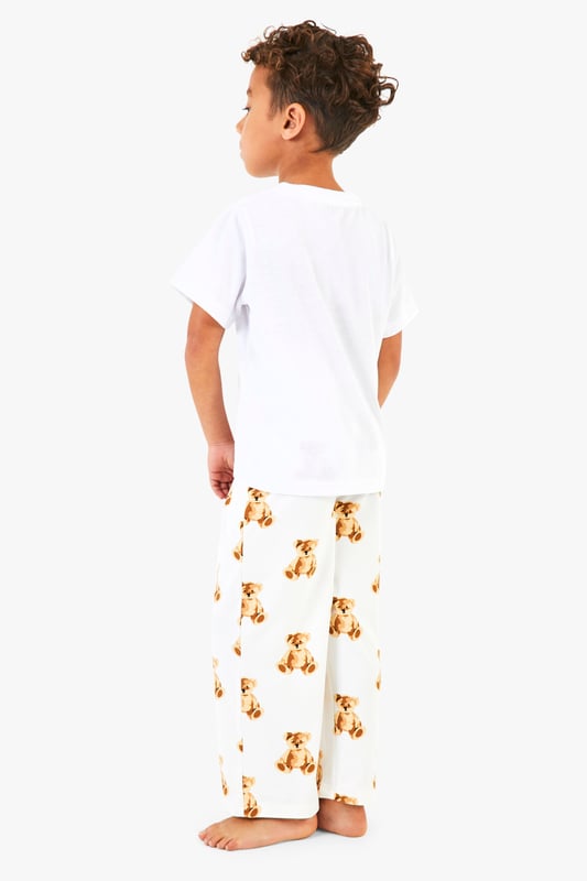 Adorable bear print pyjama bottoms
        Comfortable short-sleeved white top
        Matching set for the whole family
        Relaxed fit for ultimate comfort
        Perfect for festive celebrations
    
    Embrace the holiday spirit with this charming Kinder Br Familien Pyjama-Set from Boohoo. This delightful ensemble features a cosy white short-sleeved top paired with playful bottoms adorned with an enchanting bear print. The relaxed fit ensures maximum comfort for lounging at home or opening presents on Christmas morning. Ideal for creating cherished family moments, this set allows you to coordinate with your loved ones for a picture-perfect holiday look. Whether you're settling in for a festive film night or preparing for Santa's arrival, these pyjamas will keep you feeling snug and stylish. Add a pair of fluffy slippers and a warm dressing gown for those chilly winter evenings, and you're all set for a magical Christmas season.