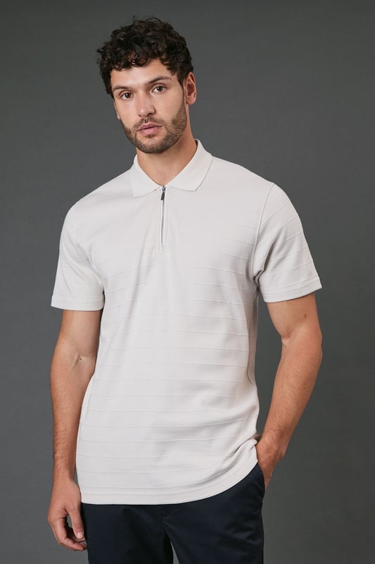 Textured stripe pattern adds subtle visual interest to this classic polo design
        Quarter-zip neck detail offers versatile styling options and a contemporary twist
        Comfortable cotton fabric ensures breathability for all-day wear
        Neat collar with ribbed finish maintains its shape throughout the day
        Relaxed short sleeves provide ease of movement for casual activities
    
    This Burton textured stripe polo combines timeless appeal with modern detailing, perfect for the man who appreciates classic style with a contemporary edge. The quarter-zip neck allows you to customise your look throughout the day, whether partially unzipped for a relaxed pub lunch or fully zipped for a smarter finish. Pair with dark trousers as shown for an effortlessly smart-casual ensemble that works brilliantly for family gatherings or weekend outings. The textured stripe pattern adds subtle sophistication while maintaining versatility. For summer barbecues or casual sporting events, team with chino shorts and trainers, or layer under a lightweight jacket when the temperature drops. Machine washable and easy to maintain, this polo represents the perfect balance of comfort and style for your everyday wardrobe.