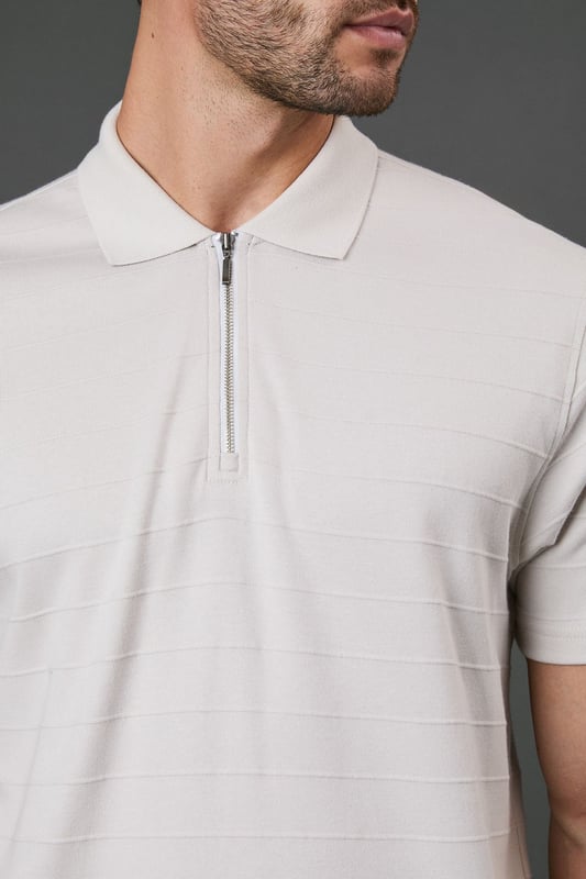Textured stripe pattern adds subtle visual interest to this classic polo design
        Quarter-zip neck detail offers versatile styling options and a contemporary twist
        Comfortable cotton fabric ensures breathability for all-day wear
        Neat collar with ribbed finish maintains its shape throughout the day
        Relaxed short sleeves provide ease of movement for casual activities
    
    This Burton textured stripe polo combines timeless appeal with modern detailing, perfect for the man who appreciates classic style with a contemporary edge. The quarter-zip neck allows you to customise your look throughout the day, whether partially unzipped for a relaxed pub lunch or fully zipped for a smarter finish. Pair with dark trousers as shown for an effortlessly smart-casual ensemble that works brilliantly for family gatherings or weekend outings. The textured stripe pattern adds subtle sophistication while maintaining versatility. For summer barbecues or casual sporting events, team with chino shorts and trainers, or layer under a lightweight jacket when the temperature drops. Machine washable and easy to maintain, this polo represents the perfect balance of comfort and style for your everyday wardrobe.