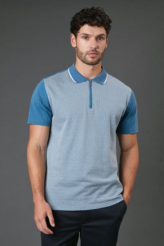 Distinctive jacquard pattern across the front body for a textured appearance
        Quarter-zip neckline with contrast tipping for a sporty finish
        Contrast solid sleeves creating a modern colour-block effect
        Ribbed collar with contrast trim for a refined touch
        Comfortable cotton fabric ideal for all-day wear
    
    This Burton jacquard polo offers a contemporary twist on a classic style. The textured pattern across the front creates visual interest whilst maintaining a sophisticated look that works perfectly for various casual occasions. Style it as shown with dark trousers and white trainers for an effortlessly smart weekend outfit, or pair with your favourite jeans for a relaxed pub lunch with mates. The quarter-zip detail adds functionality and a sporty element that nods to active lifestyles without compromising on style. Perfect for summer barbecues, casual Fridays at the office, or watching the match with friends. The contrast sleeves and collar detailing provide just enough interest to stand out from standard polos in your wardrobe, whilst the cotton construction ensures breathability and comfort throughout the day. A versatile addition to any casual wardrobe that bridges the gap between laid-back and put-together.