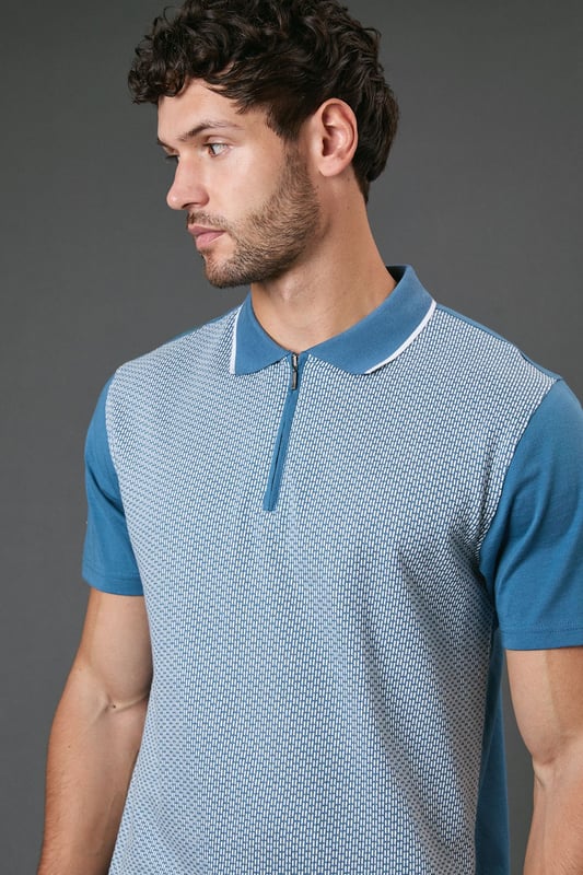 Distinctive jacquard pattern across the front body for a textured appearance
        Quarter-zip neckline with contrast tipping for a sporty finish
        Contrast solid sleeves creating a modern colour-block effect
        Ribbed collar with contrast trim for a refined touch
        Comfortable cotton fabric ideal for all-day wear
    
    This Burton jacquard polo offers a contemporary twist on a classic style. The textured pattern across the front creates visual interest whilst maintaining a sophisticated look that works perfectly for various casual occasions. Style it as shown with dark trousers and white trainers for an effortlessly smart weekend outfit, or pair with your favourite jeans for a relaxed pub lunch with mates. The quarter-zip detail adds functionality and a sporty element that nods to active lifestyles without compromising on style. Perfect for summer barbecues, casual Fridays at the office, or watching the match with friends. The contrast sleeves and collar detailing provide just enough interest to stand out from standard polos in your wardrobe, whilst the cotton construction ensures breathability and comfort throughout the day. A versatile addition to any casual wardrobe that bridges the gap between laid-back and put-together.
