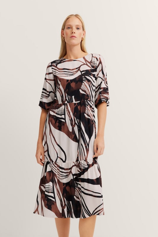 Das bugatti Sommerkleid aus 100  Prozent Viskose vereint zeitlose Eleganz mit modernen Details. Die fließenden Volants und die Teilungsnähte sorgen für eine feminine Silhouette, während praktische Seitennahttaschen und kürzeren Ärmel mit 1-Knopf-Manschette für maximalen Tragekomfort sorgen. Perfekt für stilvolle Auftritte an warmen Tagen!