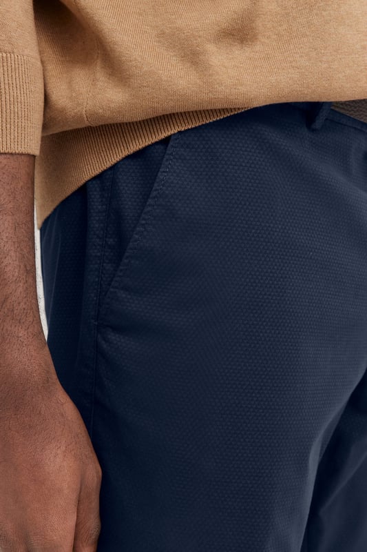 Die bugatti Chino mit ´Tapered Fit`Passform kombiniert einen modernen Schnitt mit flexiblem Komfort dank Elastananteil. Französische Taschen und eine elegante Leistentasche sorgen für ein stilvolles Design, während der Metall-Reißverschluss einen hochwertigen Akzent setzt. Perfekt für einen smarten, zeitgemäßen Look.