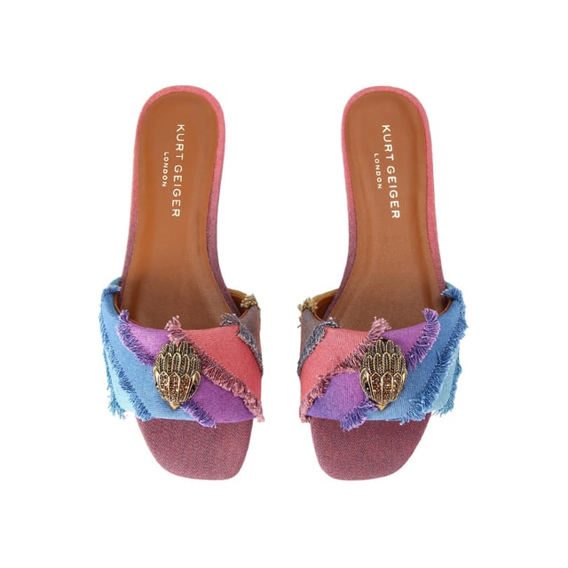 The Kurt Geiger Kensington Flat Sandal, an addition to the Kensington Collection, is crafted from a bleached denim in the iconic rainbow stripe design. The antiqued brass eagle head features crystals and black eyes on the strap.