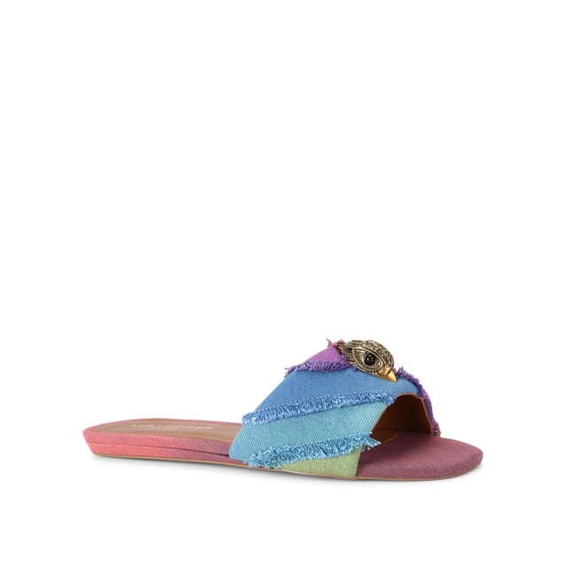 The Kurt Geiger Kensington Flat Sandal, an addition to the Kensington Collection, is crafted from a bleached denim in the iconic rainbow stripe design. The antiqued brass eagle head features crystals and black eyes on the strap.