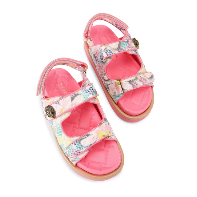 The Kurt Geiger Orson sandal features a canvas fabric upper with watercolour style floral print. The straps are velcro with an antiqued brass eagle head emblem sat on top.