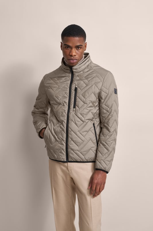 Ervaar het comfort en de stijl van de bugatti blouson in een moderne gewatteerde look. Deze lichtgewicht nylon blouson is ideaal voor op reis en biedt optimaal comfort en warmte met zijn opstaande kraag, gebreide manchetten aan de mouwen en romp en gevoerde voorkant - zonder gebruik van echt dons. Er is ook een praktische zak met rits op de borst!