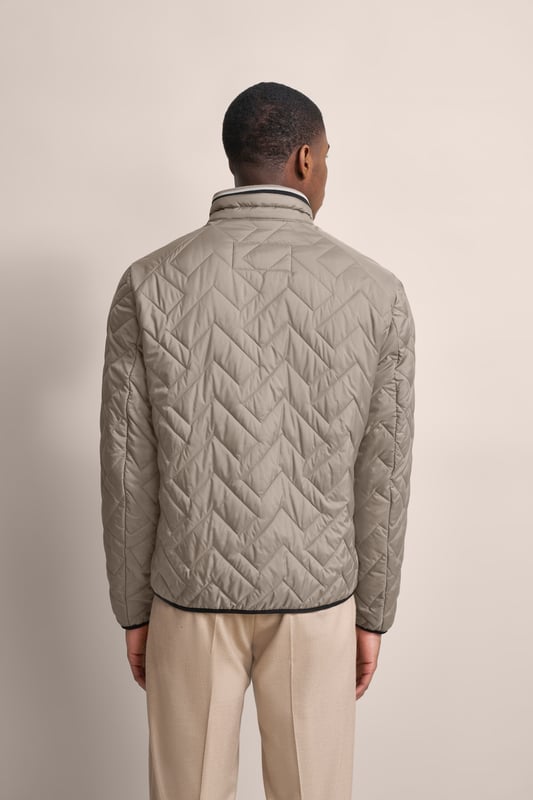 Ervaar het comfort en de stijl van de bugatti blouson in een moderne gewatteerde look. Deze lichtgewicht nylon blouson is ideaal voor op reis en biedt optimaal comfort en warmte met zijn opstaande kraag, gebreide manchetten aan de mouwen en romp en gevoerde voorkant - zonder gebruik van echt dons. Er is ook een praktische zak met rits op de borst!