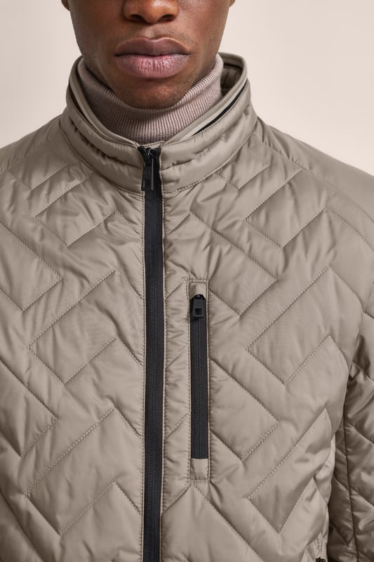 Ervaar het comfort en de stijl van de bugatti blouson in een moderne gewatteerde look. Deze lichtgewicht nylon blouson is ideaal voor op reis en biedt optimaal comfort en warmte met zijn opstaande kraag, gebreide manchetten aan de mouwen en romp en gevoerde voorkant - zonder gebruik van echt dons. Er is ook een praktische zak met rits op de borst!