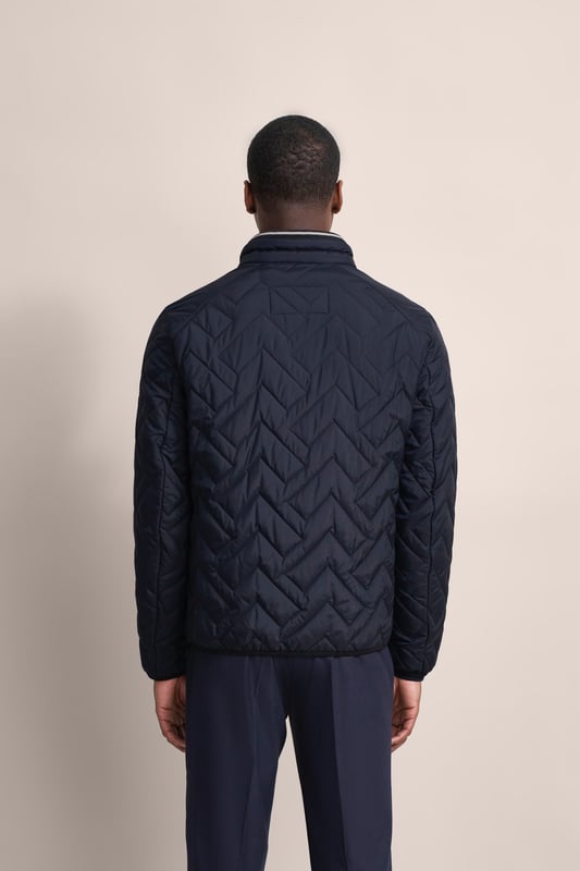 Ervaar het comfort en de stijl van de bugatti blouson in een moderne gewatteerde look. Deze lichtgewicht nylon blouson is ideaal voor op reis en biedt optimaal comfort en warmte met zijn opstaande kraag, gebreide manchetten aan de mouwen en romp en gevoerde voorkant - zonder gebruik van echt dons. Er is ook een praktische zak met rits op de borst!