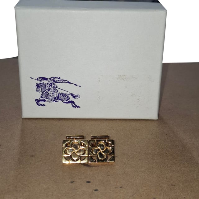 VINTAGE, RRP AS NEW
Add a touch of British charm to your formalwear with the Burberry Clover Leaf Cufflinks, crafted in gold-finished sterling silver for a refined yet distinctive look. The clover leaf design symbolizes luck and elegance, making them a thoughtful detail for special occasions or everyday sophistication. **Styling tip:** Wear them with a crisp French cuff shirt and a tailored blazer to elevate your ensemble with subtle luxury.

Burberry Clover Leaf Cufflinks in Gold Sterling Silver

Condition: Excellent
Signs of wear:  No sign of wear.
Packaging: None
Color: Gold
Material: Metal | 1sterling silver
Size: One Size | One Size
Measurements: 
SKU: NAPPUGBOT504391W