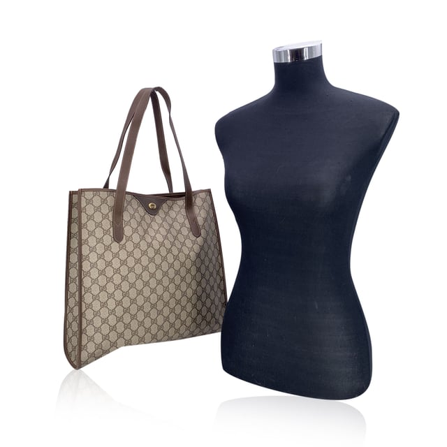 VINTAGE, RRP AS NEW
Step into the understated elegance of the past with this vintage Gucci tote bag, a refined piece from the iconic Gucci Accessory Collection. Crafted in beige monogram canvas, it proudly showcases the unmistakable GG pattern that defined an era of quiet luxury. Trimmed in rich brown genuine leather, this tote exudes both character and classic Italian craftsmanship.  The magnetic button closure opens to a beige fabric-lined interior, complete with a practical side zip pocket for your essentials. Inside, the original 'GUCCI Accessory Collection - Made in Italy' leather tag remains intact, a subtle nod to the brand's heritage and ity.  A timeless piece for those who appreciate vintage luxury with soul, this Gucci tote is more than a bag-it's a story carried on the arm. Condition Rating: B - VERY GOOD CONDITIONCondition Details: Gently used. Minimal wear of use on leather trim. A small white mark on canvas on the bottom. Please check the photos carefully and ask if you need to know more details or if you have any doubts.Measurements (cm):Depth: 11.4Height: 36.8Length: 36.8Other Details: Dustbag? NoKeys? NoBox? No Measurments:  width: 114 mm length: 368 mm height: 368 mm strap length: 0 mm handle drop: 0 mm