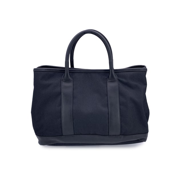 VINTAGE, RRP AS NEW
Understated, refined, and undeniably rare, this Vintage Yves Saint Laurent Pour Homme tote captures the quiet confidence of YSL's menswear line in a form that still feels effortlessly modern. Crafted from durable black nylon canvas and accented with sleek black leather trim, this tote is a functional piece with subtle designer distinction.  At the front, a silver metal Yves Saint Laurent tab adds a discreet touch of luxury, while the magnetic button closure opens to reveal a black nylon canvas lining-clean, simple, and timeless. Inside, a zip pocket offers secure storage, and the original 'Yves Saint Laurent' tag affirms the bag's ity. A true collector's bonus: the 'Yves Saint Laurent Pour Homme' shop hang tag remains thoughtfully attached, hinting at the bag's pristine and possibly unused Condition Rating: A - EXCELLENTCondition Details: Gently used. Yves Saint Laurent hang tag still attached. Please check the photos carefully and ask if you need to know more details or if you have any doubts.Measurements (cm):Depth: 15.2Height: 24.1Length: 35.6Other Details: Dustbag? NoKeys? NoBox? No Measurments:  width: 152 mm length: 356 mm height: 241 mm strap length: 0 mm handle drop: 0 mm