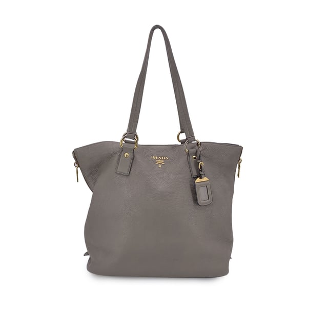 VINTAGE, RRP AS NEW
This beautiful item will come with a Certificate of ity provided by Entrupy. The certificate will be provided at no further cost  Elevate your everyday with this beautiful PRADA tote bag, crafted in luxurious grey taupe textured leather-a timeless neutral that pairs effortlessly with any look. Showcasing PRADA's signature blend of elegance and functionality, this tote features structured double top handles and refined silver-tone Prada lettering on the front, adding a touch of quiet sophistication.  The top opens with a button closure to reveal a spacious main compartment, fully lined in PRADA's iconic jacquard fabric. Inside, you'll find one zip pocket and one open pocket to keep your essentials neatly organized. A 'PRADA Milano' tag and a discreet numbered label tucked inside the interior pocket ensure ity.  Finished with four metal bottom feet for added protection and polish, this tote is as practical as it is chic-perfect for the modern woman who values understated luxury. Condition Rating: B - VERY GOOD CONDITIONCondition Details: Some wear of use on the upper border (please see photos). Some wear of use on the hardware. Please check the photos carefully and ask if you need to know more details or if you have any doubts.Measurements (cm):Depth: 15.2Height: 34.3Length: 36.8Other Details: Dustbag? NoKeys? NoBox? No Measurments:  width: 152 mm length: 368 mm height: 343 mm strap length: 0 mm handle drop: 0 mm