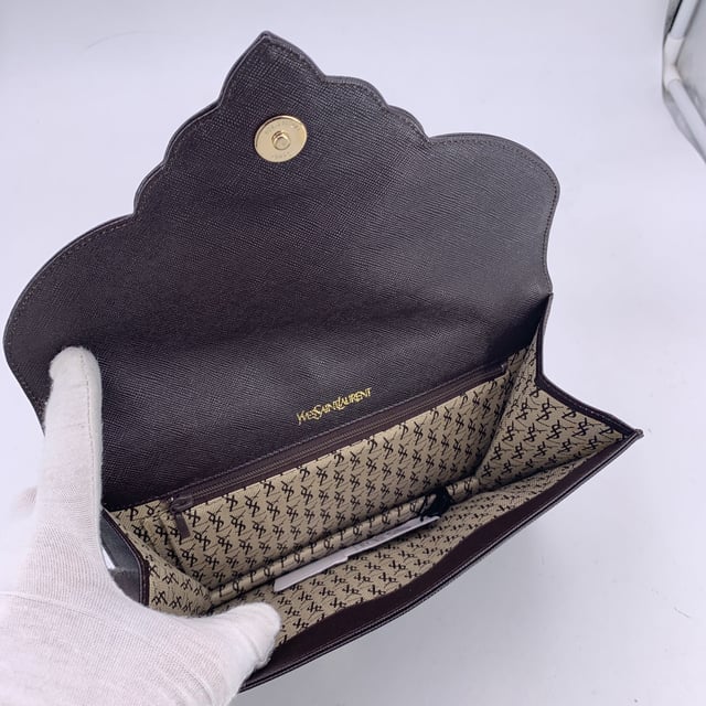 VINTAGE, RRP AS NEW
Step into timeless elegance with this vintage Yves Saint Laurent clutch bag - a true emblem of classic Parisian sophistication. Crafted in brown leather, this refined piece echoes the understated glamour of eras past. The structured silhouette is anchored by a front flap with a magnetic button closure, crowned with the iconic YSL logo - a quiet nod to one of fashion's most enduring maisons.  Open the flap to reveal a fabric-lined interior, thoughtfully designed with a side zip pocket for your evening essentials. A rear open pocket adds practicality without compromising its sleek form. Inside, the 'YVES SAINT LAURENT' embossing is a subtle reminder of its storied lineage.  Whether tucked under your arm or proudly displayed on a vanity, this vintage YSL clutch isn't just an accessory - it's a chapter of fashion history, waiting to be carried into the night. Condition Rating: A - EXCELLENTCondition Details: Gently Used. Minimal scratches on leather due to normal use. Please check the images carefully. Please ask if you need to know more details or if you have any doubts.Measurements (cm):Depth: 2.5Height: 16.5Length: 24.1Other Details: Dustbag? NoKeys? NoBox? No Measurments:  width: 25 mm length: 241 mm height: 165 mm strap length: 0 mm handle drop: 0 mm